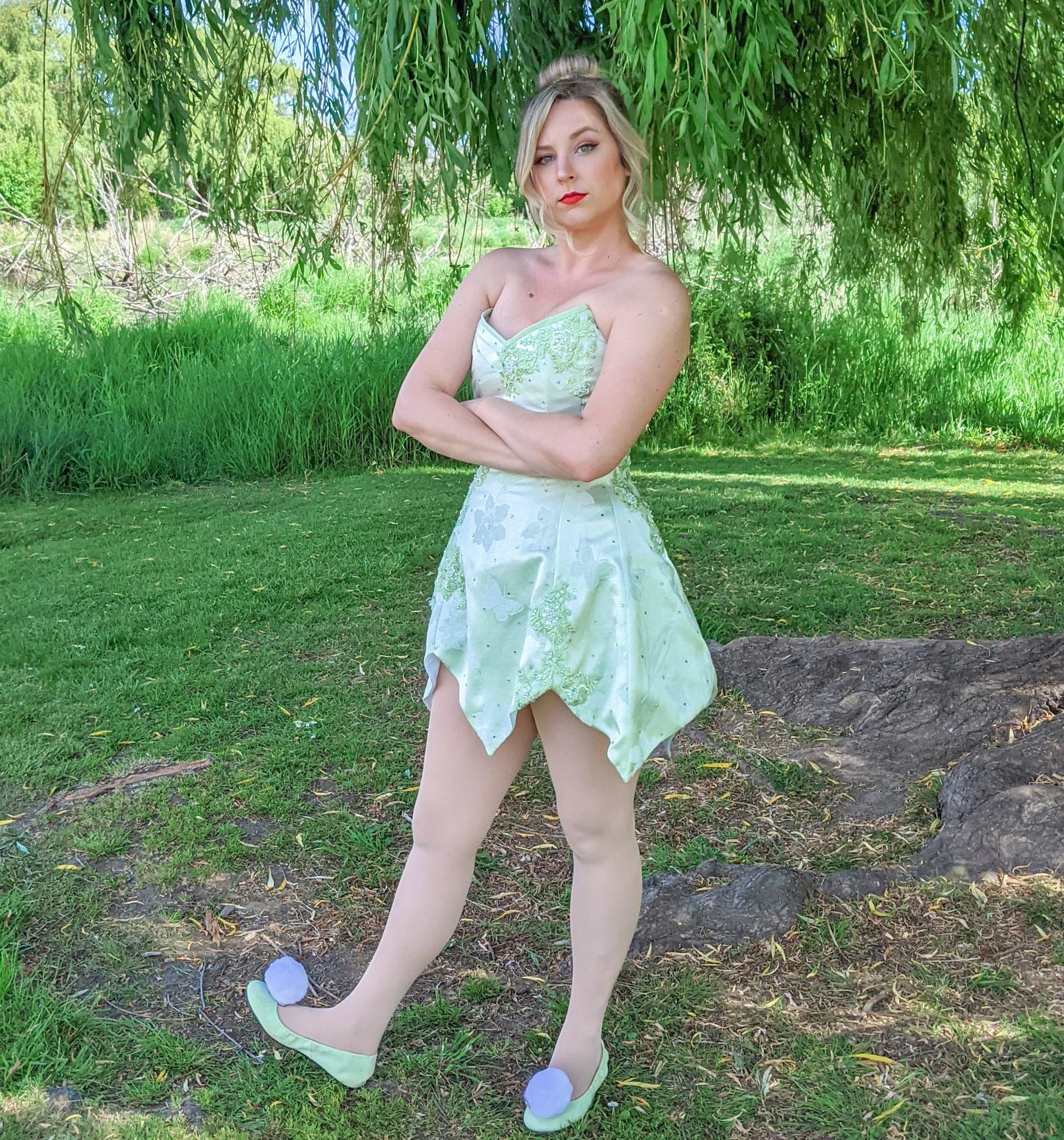 Woman in a green Tinker Bell costume beneath a willow tree